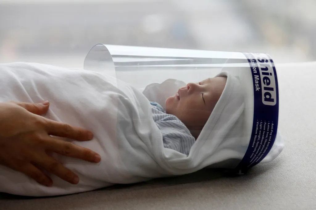 Novorozeně s ochrannou obličejovou maskou těsně před odchodem z domova k lékaři na očkování