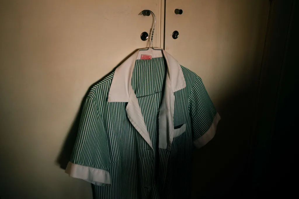 Jedna z uniforem Any Marie je připravena k práci, Lisabon, Portugalsko (One of Ana Maria’s uniforms hangs ready for work, in Lisbon, Portugal) – Když jí bylo devět let, byla Ana Marie portugalskou rodinou pod falešným příslibem vzdělání převezena z Angoly do Portugalska. Tam byla nucena přijmout nové jméno i datum narození a sloužit v domácnostech. Když jí bylo 21, podařilo se Aně Marii osvobodit