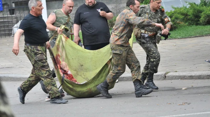 Povstalci odnášejí ze svého poškozeného štábu oběti