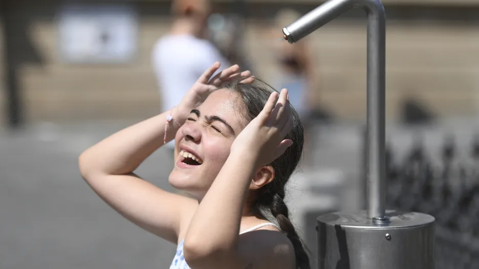 Dívka se osvěžuje u mlžítka na Staroměstském náměstí v Praze