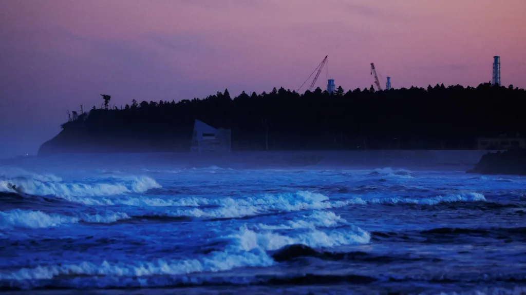 Ventilace a jeřáby uzavřené fukušimské elektrárny, pohled z pláže