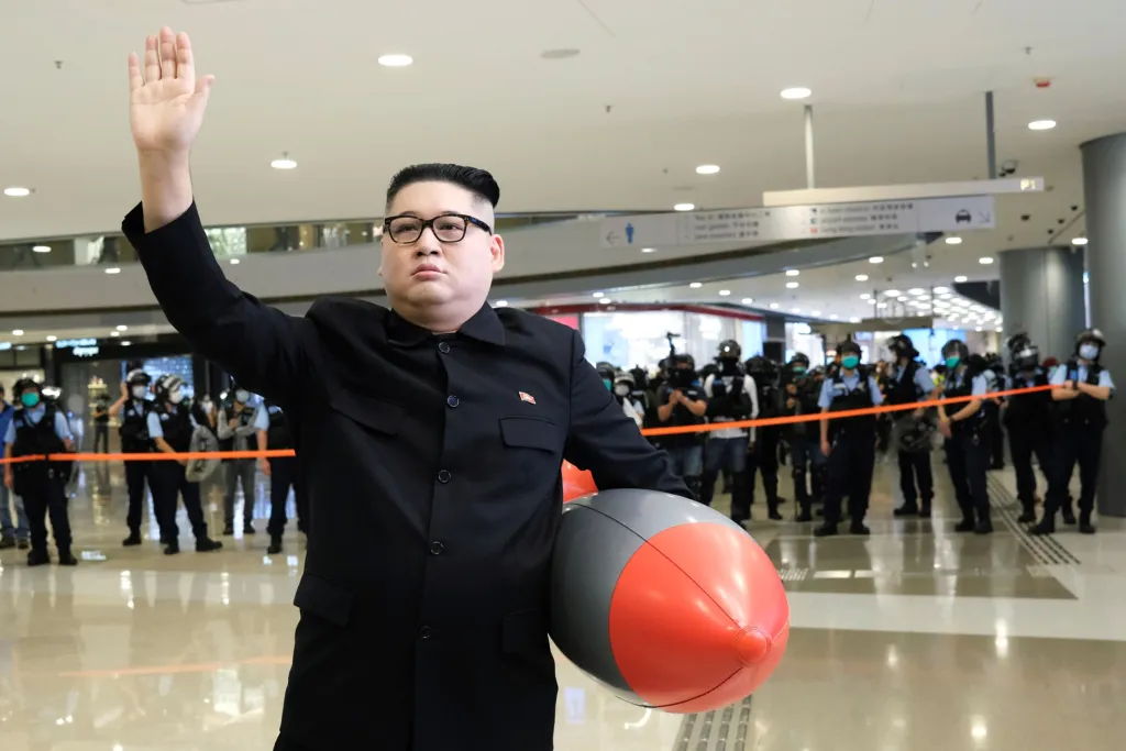 Howard X je australský dvojník (čínského původu) známého státníka Kim Čong-una. Na snímku se pohybuje v obchodním domě v Hongkongu, kde provokuje svojí přítomností policisty. Ti se snaží uklidnit situaci v místě, kde protestují lidé proti pročínským politikům