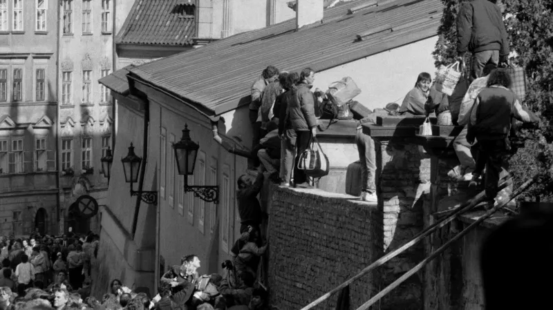 Východoněmečtí uprchlíci přelézají zeď k západoněmecké ambasádě na podzim 1989