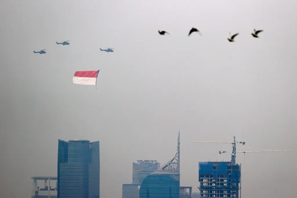 Vrtulníky indonéského letectva létají s vlajkou nad výškovými budovami během oslav dne nezávislosti v hlavním městě Jakartě