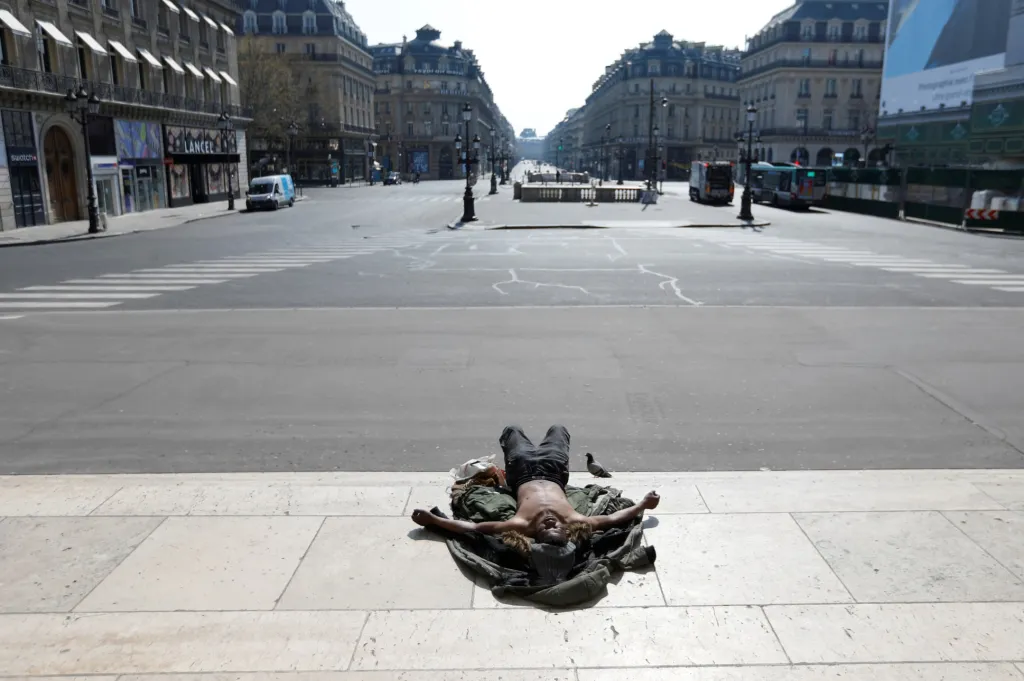 Bezdomovec leží na místě, kde jindy procházejí tisíce lidí na schodech poblíž opuštěného náměstí Place de l'Opera v Paříži