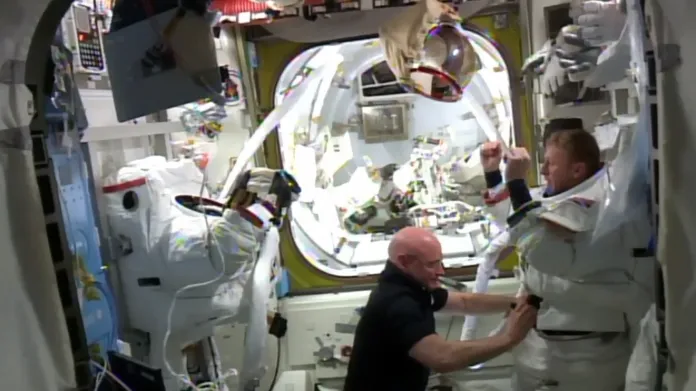 Velitel ISS Scott Kelly pomáhá Timu Peakovi ze skafandru