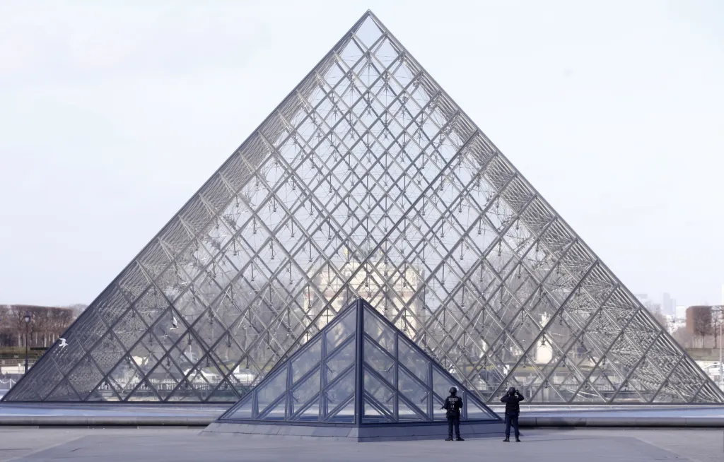 Pyramida má čtvercovou základnu s délkou hrany 35 metrů a výšku 20,6 metru. Skládá se ze 603 kosočtvercových a 70 trojúhelníkových dílů. Zastřešuje centrální prostor pokladen a informačních přepážek Muzea Louvre. Na snímku policejní hlídka před pyramidou v únoru 2017.