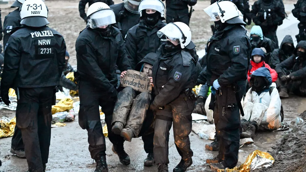 Policisté odnášejí ekologickou aktivistku během protestu v Lützerathu