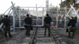 Policisté na makedonské straně  střeží bránu v žiletkovém plotu před náporem migrantů z řecké strany hranice