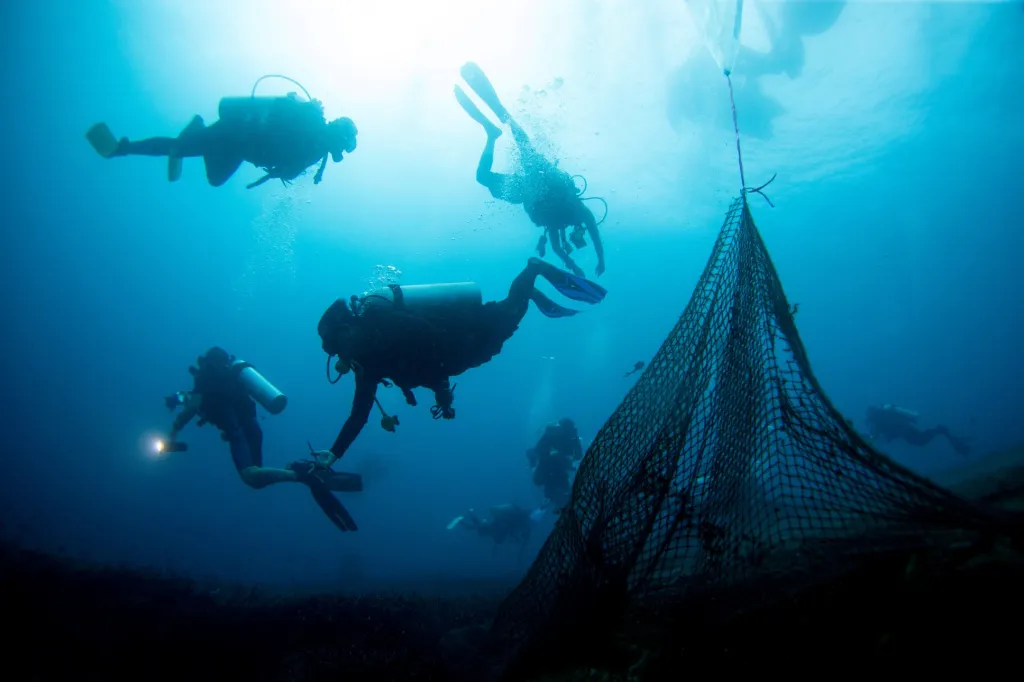 Opuštěné rybářské sítě pokrývající korálový útes v chráněné oblasti Ko Losin. Skupina dobrovolných potápěčů, vědecké centrum pro výzkum pobřeží a thajské královské námořnictvo odstraňují v této oblasti sítě “duchů”