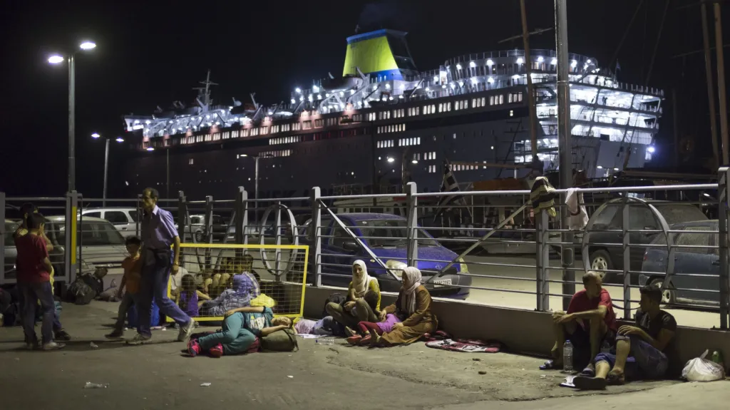 Uprchlíci nocují v přístavu Kos. V pozadí kotví trajekt Eleftherios Venizelos