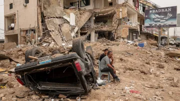 Lidé v Libanonu sedí před budovou, na kterou zasáhly izraelské údery, 18. dubna