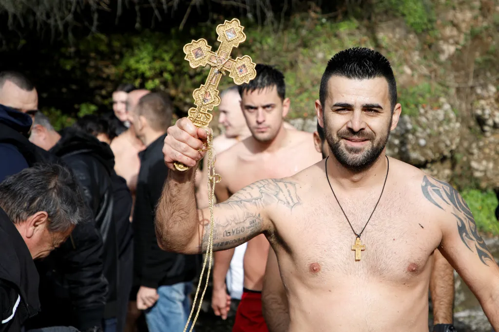 Věřící v Podgorici v Černé Hoře zvedá kříž, který vytáhl z řeky