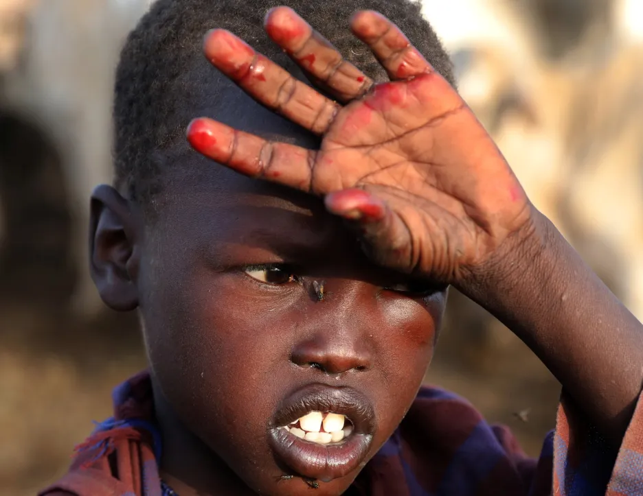 Chlapec má ruce od krve poté, co jeho soukmenovci zabili krávu tradičním způsobem
