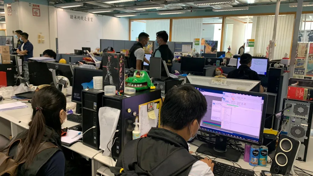 Policisté prohlížejí počítače v redakci deníku Apple Daily