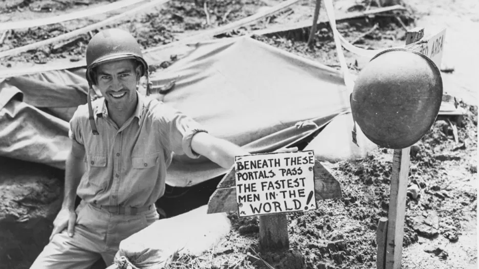 Bombový kryt na Guadalcanalu a nápis na ceduli: „Tímto vchodem běhají nejrychlejší muži na světě“