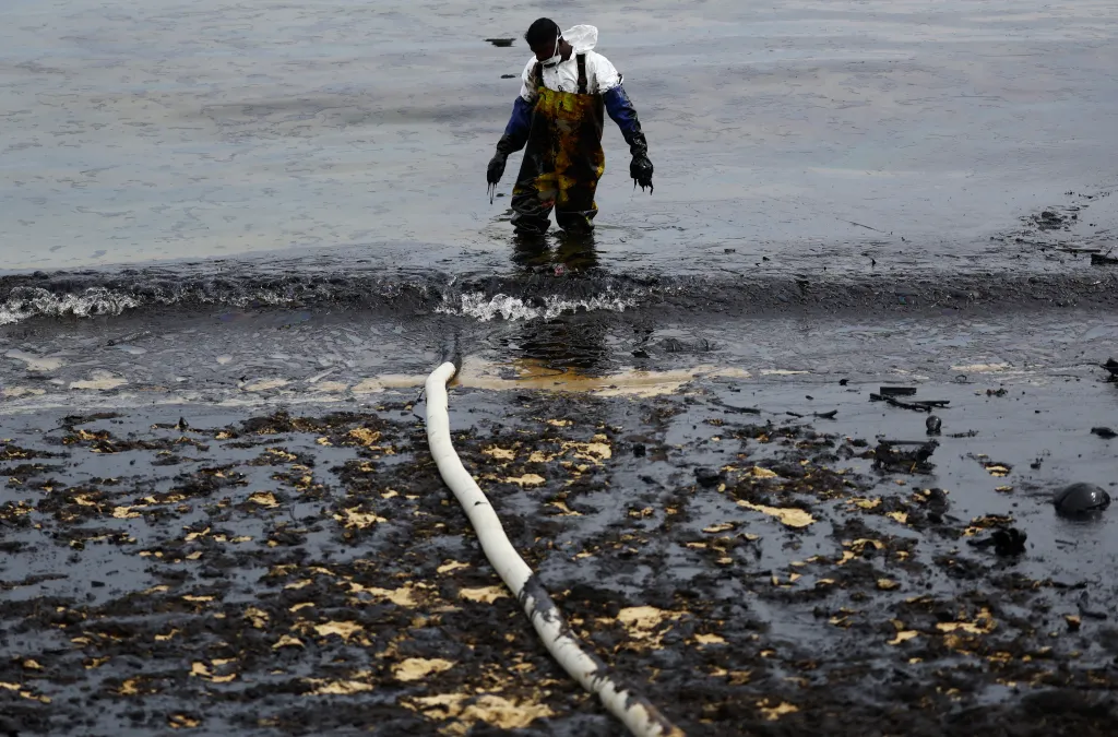 Pracovník při odstraňování ropné skvrny uvolňuje hadici od čerpadla
