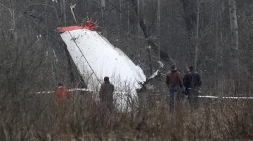 Lidé stojí u trosek polského vládního letadla Tupolev Tu-154, které se zřítilo u letiště ve Smolensku (10. dubna 2010)