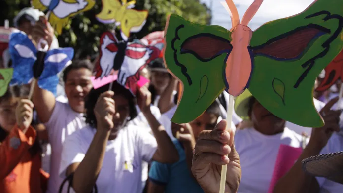 Lidé držící symbol sester Mirabaových - papírového motýla při pochodu proti násilí na ženách