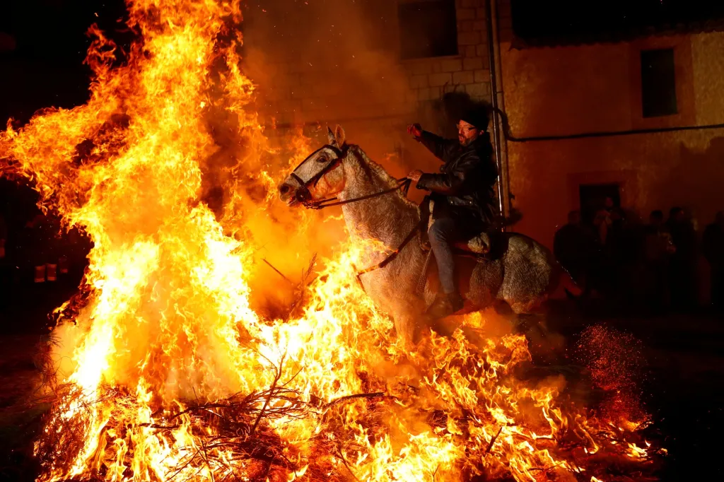 Jeden z účastníků kontroverzní oslavy Las Luminarias přejíždí na koni přes oheň ve španělské vesnici San Bartolomé de Pinares