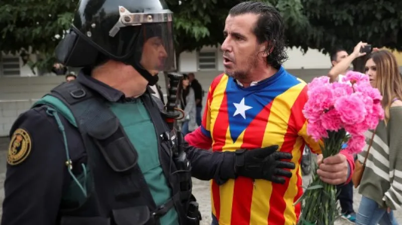 Muž s esteladou (katalánskou separatistickou vlajkou) a karafiáty stojí proti členovi civilní španělské gardy v Sant Julia de Ramis,  Autor: Albert Gea,  Zdroj: Reuters