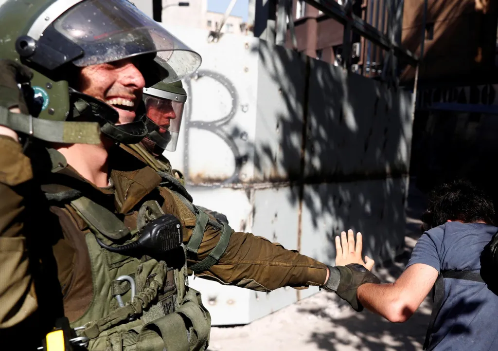 Na této fotografii policista nezatýká protestujícího, ale pomáhá člověku, který zakopnul a upadl. Chile, 20. listopadu 2019