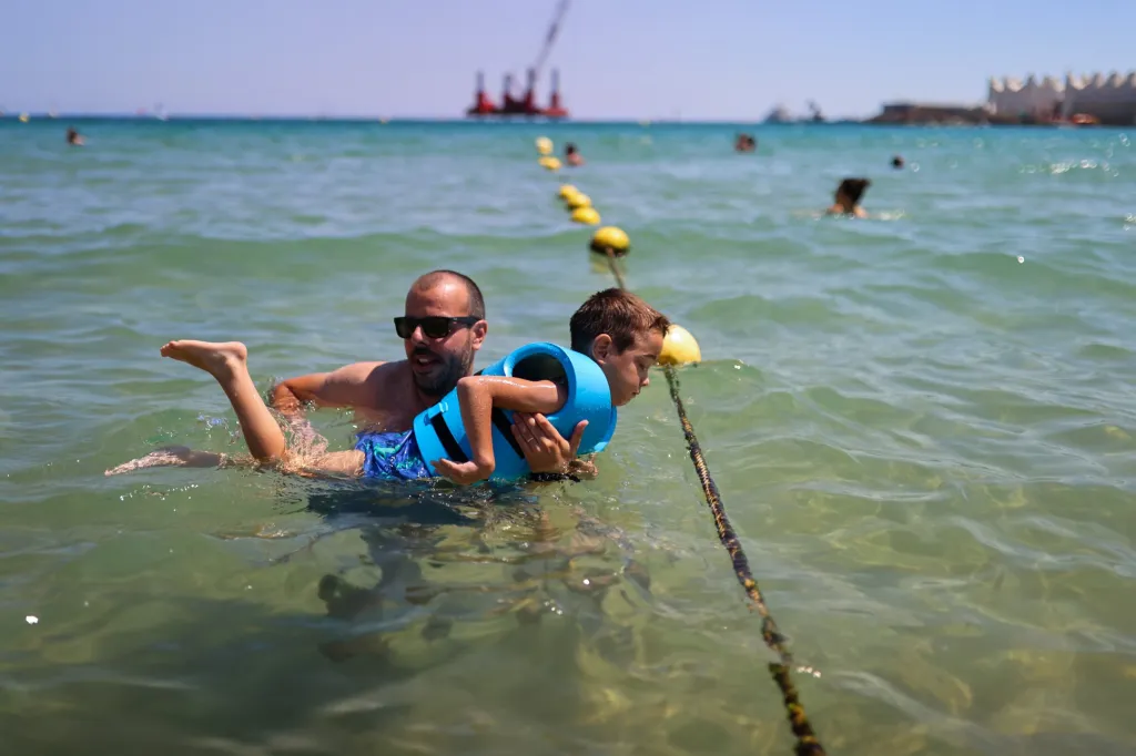 Plavčíci z pláže Nova Icaria ve Španělsku pomáhají lidem se zdravotním postižením s plaváním v moři