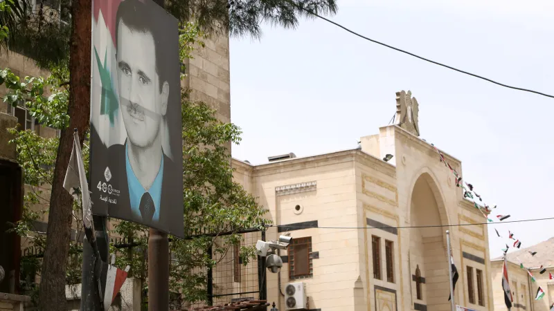 Billboard s diktátorem Bašárem Asadem u budovy syrského parlamentu v Damašku (snímek z roku 2021)