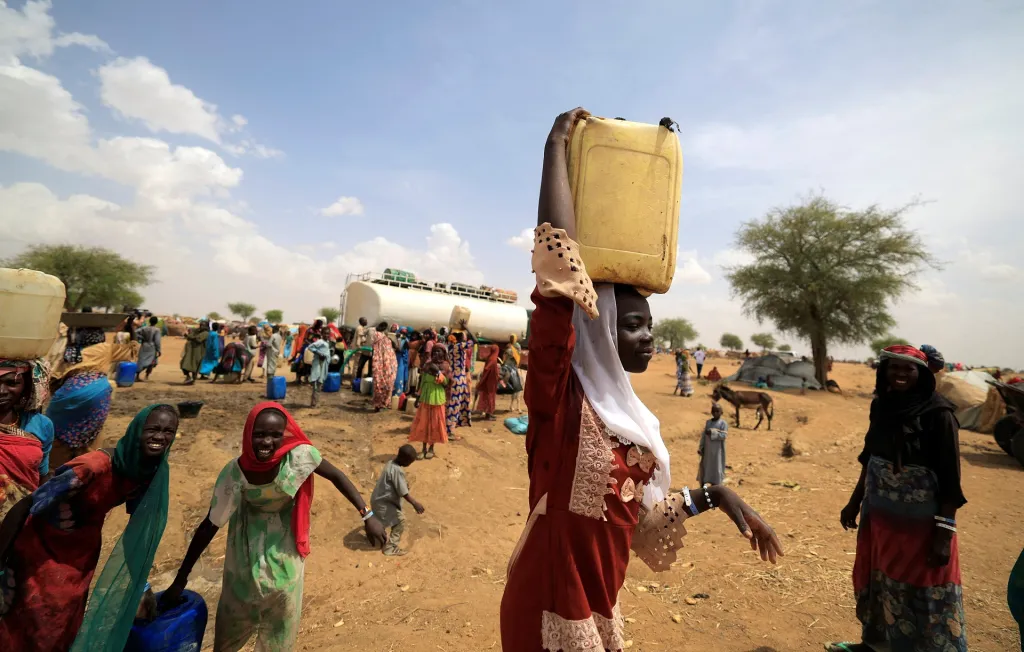 Súdánka s kanystrem vody míří ke svému přístřešku v uprchlickém táboře
