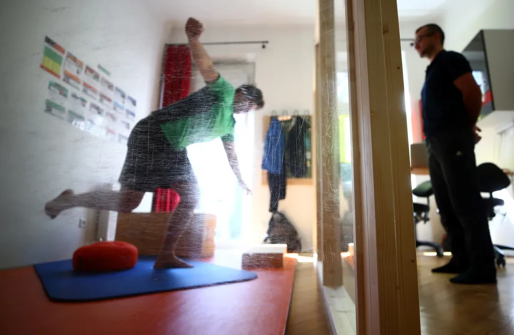 Fyzioterapeut Alan využívá během cvičení s klienty skleněnou stěnu, která odděluje jejich osobní prostor. Foceno ve Vídni