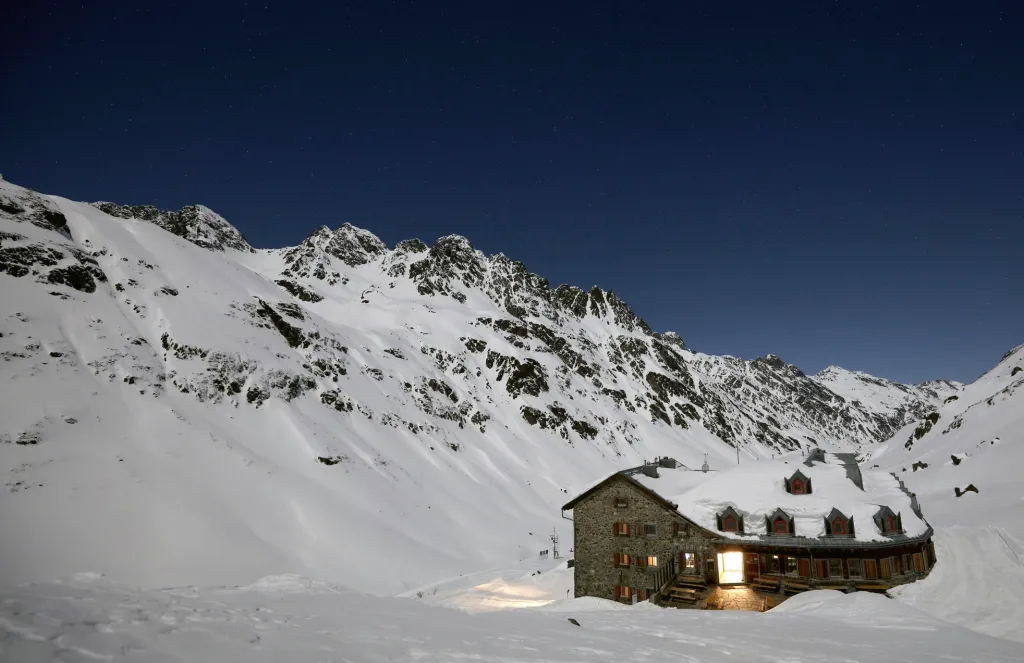 Chata Jamtal, kde vědci přespávají, září v noci v zasněženém údolí poblíž Galtueru