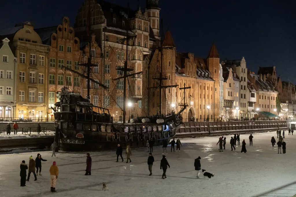 Lidé se procházejí a bruslí na zamrzlé řece Motlawě v polském Gdaňsku