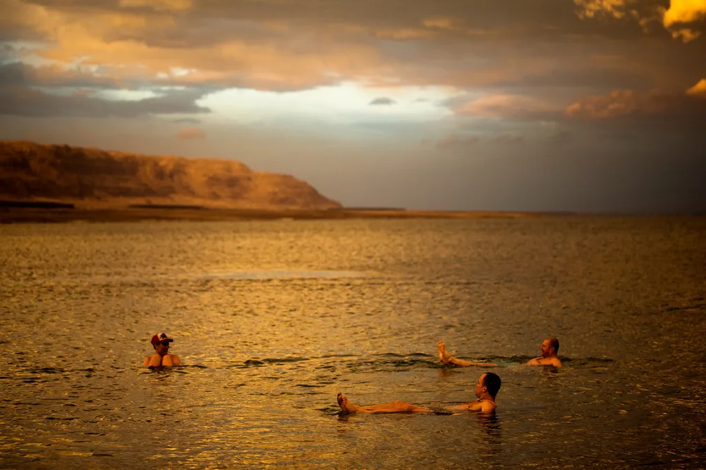 Polští turisté si užívají koupele v Mrtvém moři při západu slunce. Unikátnímu jezeru a nejhlubšímu místu na planetě (430 metrů pod mořskou hladinou) hrozí úplné vyschnutí