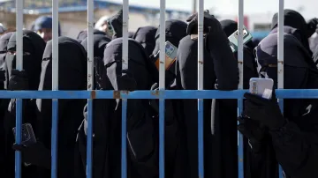 Ženy v detenčním táboře al-Húl s příbuznými členů IS hledí přes plot