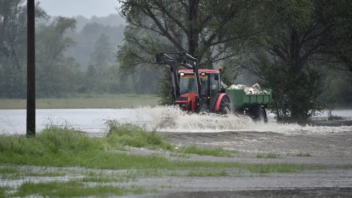 Traktor s vlekem projíždí na zaplavené cestě ve Višňové