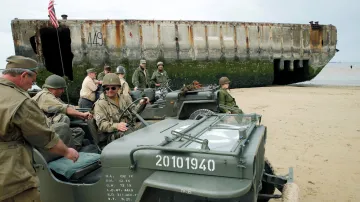 Nadšenci historie řídí historický jeep během ukázky vylodění v Den D na pláži v Arromanches na pobřeží Normandie