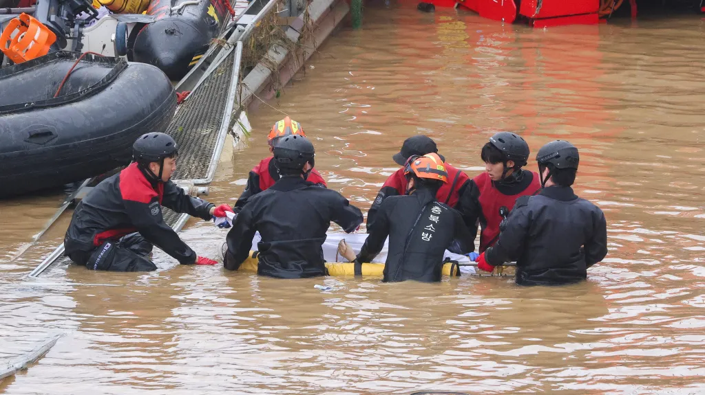 Záchranáři přenáší tělo oběti nalezené v tunelu poblíž Čchongdžu
