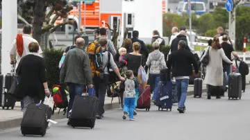 Cestující na letišti při pěších přesunech mezi terminály během stávky, při níž je místní hromadná doprava mimo provoz
