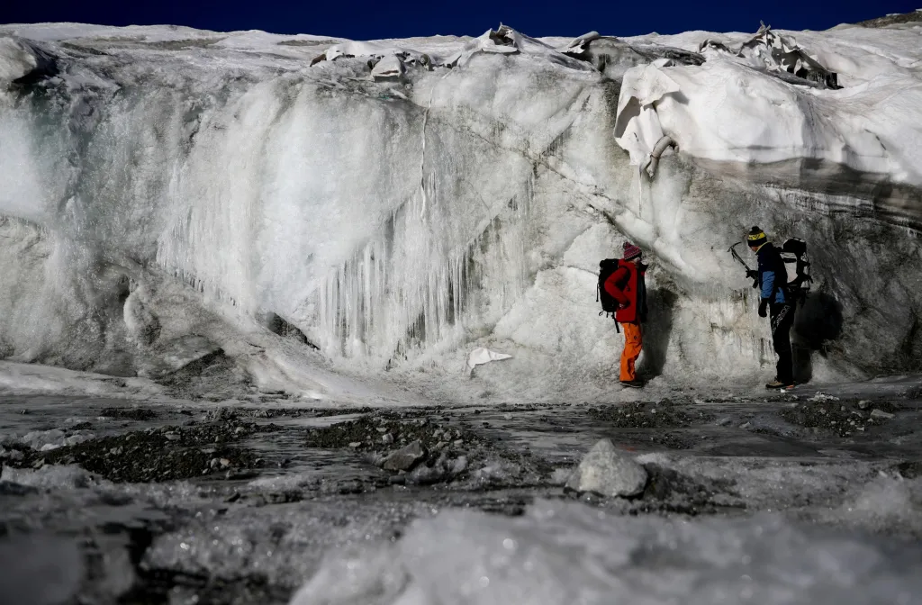 Glacioložka Andrea Fischerová a environmentální fyzik Pascal Bohleber si prohlíží rozdíl tloušťky části ledovce Schaufelferner v části, kde je pokryt speciální tkaninou chránící led před sluncem a teplem a v části, která pokryta není