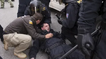 Zasažený policista po střetu pořádkové služby s demonstranty v ulici J. Bendy