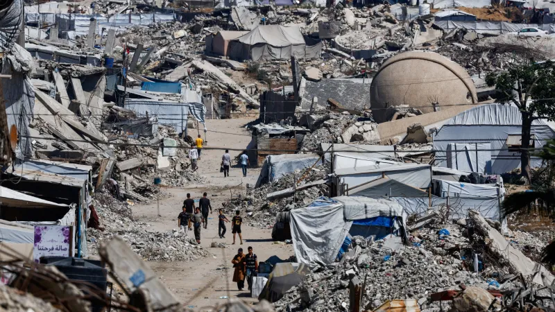 Palestinci procházejí kolem trosek obytných budov v uprchlickém táboře Džabálija na severu Pásma Gazy (12. června 2026)