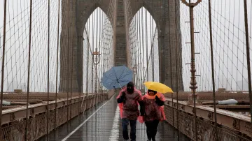 Lidé procházejí v silném větru po Brooklynském mostu