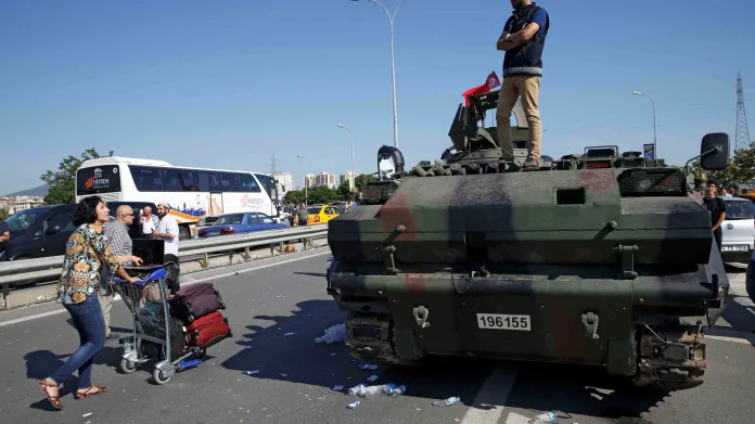 Žena se zavazadly prochází kolem vojenského vozidla před letištěm Sabiha  v Istanbulu
