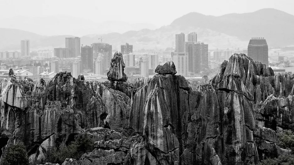 Vítězná fotografie v kategorii Street Photography s názvem Open-air toaleta. Kamenný les na jihu Číny vznikl dlouhodobým procesem eroze. V pozadí jsou hory tvarované během milionů let. A mezi nimi město mrakodrapů vytvořené v relativním okamžiku kontrastuje s krajinou, která nikdy nezestárne. Navzdory tomu se zdá, jako by obě formy krajiny spolu rozvíjely tichý dialog