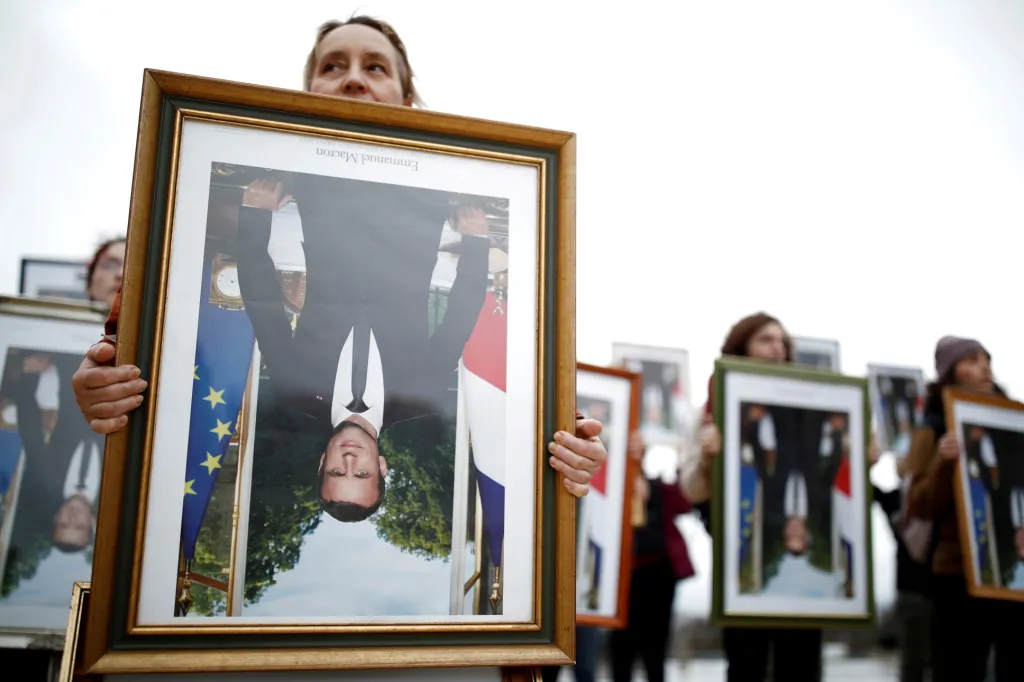 Francouzští klimatičtí aktivisté drží obráceně portréty prezidenta Emmanuela Macrona během protestu před Eiffelovou věží