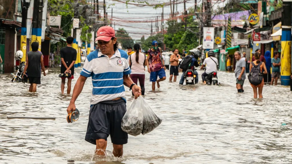 Lidé ve filipínském městě Bacoor se brodí vodou po bouři Nalgae