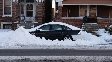 Auto zůstává částečně zasypané odhrnutým sněhem podél obytné ulice po zimní bouři v oblasti St. Louis v Missouri