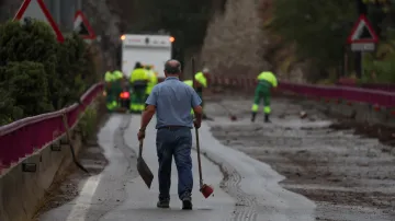 Dělníci odstraňují naplavené bahno z mostu
