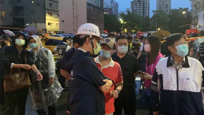 Lidé čekají před budovou zasaženou ohněm na zprávu o osudu svých příbuzných