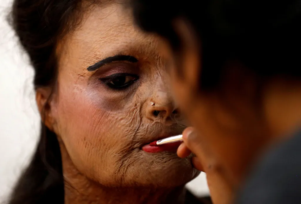 Oběť útoku kyselinou sírovou aplikuje make-up v zákulisí před módní přehlídkou na Mezinárodní den žen na okraji Bombaje. Podobných případů, většinou rukou žárlivých manželů, jsou v Indii tisíce.